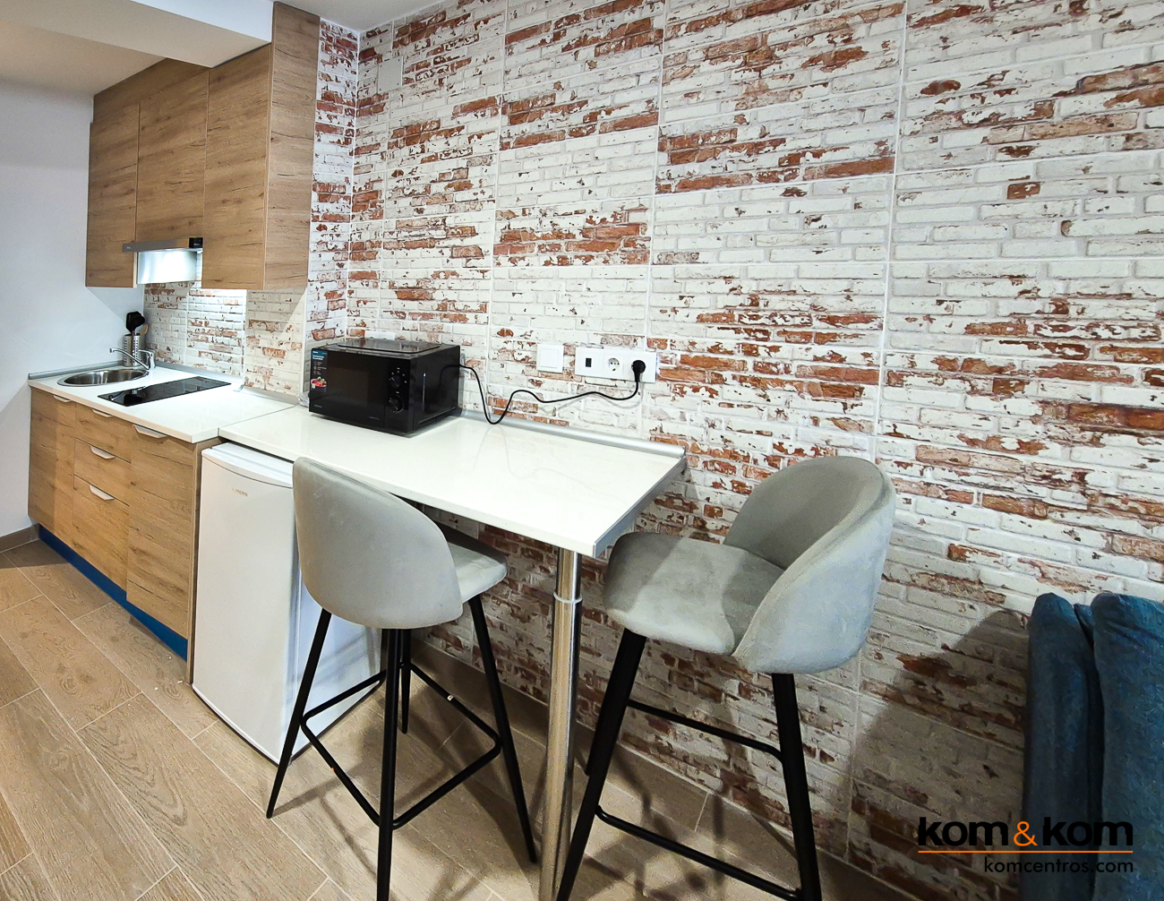 cocina peque&ntilde;a de madera con barra taburetes en apartamento tur&iacute;stico.